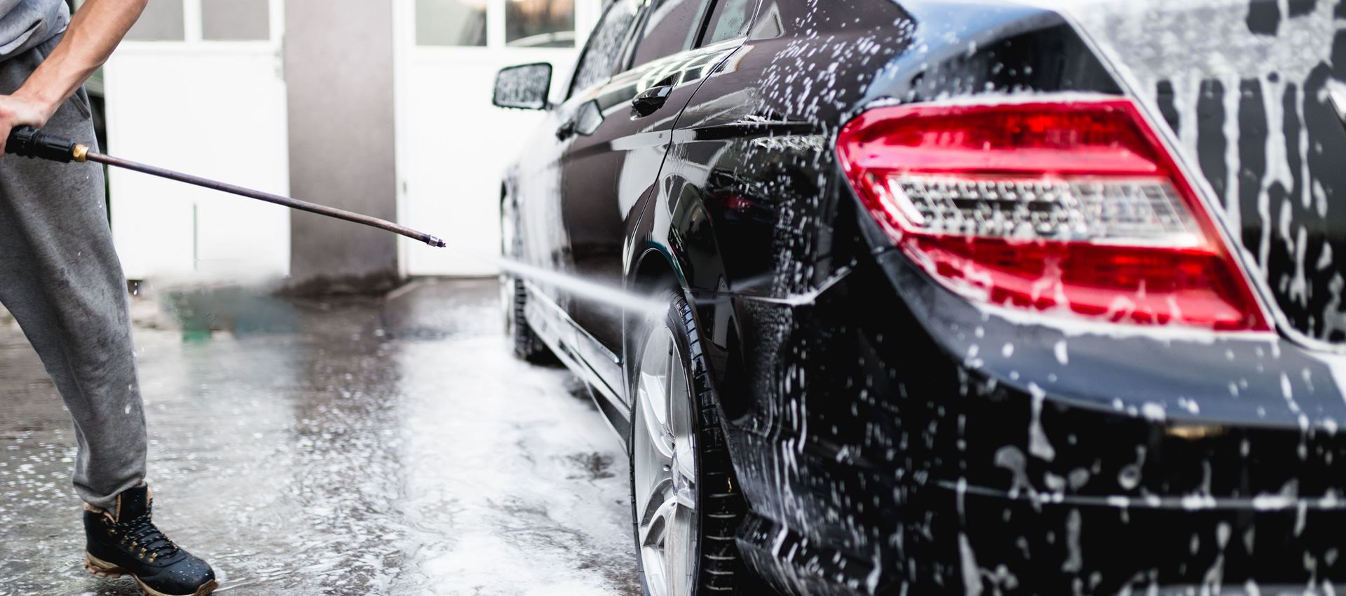 car being professionally washed, likely at a commercial hand car wash center