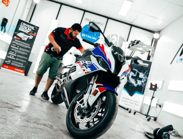 Sports bike being detailed, with technicians working on cleaning and polishing the bike’s exterior.