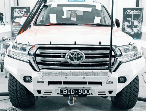 White Toyota 4x4 in a showroom setting, showcasing its meticulously detailed and spotless exterior.